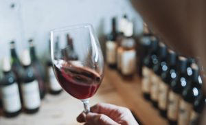 A hand holding a wine glass in a wine cellar